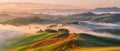 Undulating hills shrouded in mist under a pastel dawn sky create a tranquil and dreamy landscape. Royalty Free Stock Photo