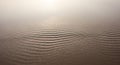 Undulating sand dunes with subtle, rhythmic ripples stretch across the foreground. The texture Royalty Free Stock Photo