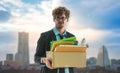 Unemployed Business man carrying a packed box with upset expression for unemployment concept with modern city background Royalty Free Stock Photo