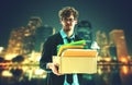 Unemployed Business worker carrying a packed box with upset expression for unemployment concept with night business city Royalty Free Stock Photo