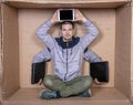 Unemployed businessman sits in a cardboard office, has some hands