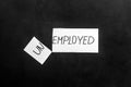 Unemployed - employed - torn paper sheet on black background top view. Hiring concept.