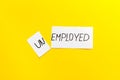 Unemployed - employed - torn paper sheet on yellow background top view. Hiring concept.