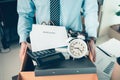 Unemployed hold cardboard box and resignation letter, dossier, alam clock, coffee cup, calculator and drawing tube in box. Quiting Royalty Free Stock Photo