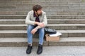 Unemployed man in depression sits on the stairs outdoors. Economic crisis, failure, despair. Unemployment and layoffs concept Royalty Free Stock Photo