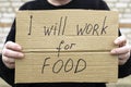 Unemployed person holding a cardboard sign with a inscription i will work for food