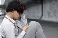 Unemployed stressed young Asian business man with hands on face and using mobile smart phone. Failure and layoff concept