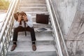 Unemployed stressed young Asian business man with laptop in suit covering face with hands sitting on the stairs. Failure and