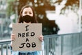 An unemployed women holding a paper sign writing a message saying she needs a job Royalty Free Stock Photo