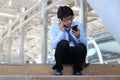Unemployed young Asian man looking for job in mobile smart phone. Unemployment concept