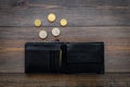 Unemployment concept. Lack of money. Coins fall out of wallet on dark wooden background top view