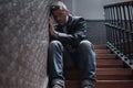 Unemployment and divorce - dramatic lifestyle portrait of sad and depressed man on his 40s sitting indoors on staircase thoughtful