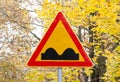 Uneven Road Sign on yellow autumn leaves background. Royalty Free Stock Photo