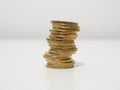 Uneven stack of One Euro coins on a white desk about to topple over