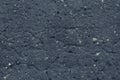 Uneven surface of dark gray concrete wall close-up. Rough texture of grey cement wall with small white stones. Dark asphalt textur Royalty Free Stock Photo