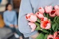 Unexpected moment in routine everyday life! Cropped photo of man's hands hiding holding chic bouquet of tulips behind back