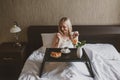 An unexpected surprise - Breakfast in bed. A woman in hotel or room looks at coffee sitting in bed, in front of her is table-tray