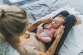 Unexperienced young mother with tattoos on her forearms sitting calmly on bed, holding her small infant baby boy on her Royalty Free Stock Photo