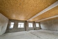 Unfinished apartment or house big loft room under reconstruction. Plywood ceiling, plastered walls, window openings, cement floor Royalty Free Stock Photo