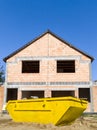 Unfinished brick house with construction skip in front Royalty Free Stock Photo
