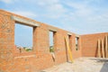 Unfinished brick house construction with windows, concrete lintels and no roof