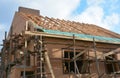 Unfinished brick house rooftop roofing construction attic trusses, wooden beams, eaves, timber, scaffolding. House roof wooden