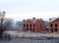 An unfinished brick houses with a wooden roof frame is still under construction. A building site