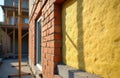 Unfinished brick wall with yellow insulation visible. Building site with scaffolding in background. Construction progress towards Royalty Free Stock Photo