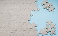 Unfinished cardboard puzzle without drawing. A blue background on the right and a few scattered pieces of the puzzle. Copy space Royalty Free Stock Photo