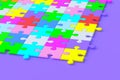 Unfinished colorful puzzle jiggle pieces on violet background