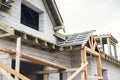 Unfinished house. Wooden roof framing with vapor barrier and dormer on block walls with windows. New modern farmhouse construction Royalty Free Stock Photo