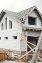 Unfinished house. Wooden roof framing with vapor barrier and dormer on block walls with windows. New modern farmhouse construction Royalty Free Stock Photo