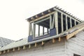 Unfinished house. Wooden roof framing with vapor barrier and dormer on block walls with windows. New modern farmhouse construction