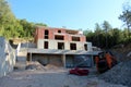 Unfinished large red building blocks family house construction site on side of small hill surrounded with building material Royalty Free Stock Photo