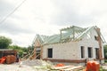 Unfinished modern farmhouse building. Wooden roof framing of mansard with dormer and aerated concrete block walls. Timber trusses Royalty Free Stock Photo