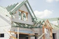 Unfinished modern farmhouse building. Wooden roof framing of mansard with dormer and aerated concrete block walls. Timber trusses