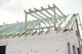 Unfinished modern farmhouse building. Wooden roof framing of mansard with dormer and aerated concrete block walls. Timber trusses Royalty Free Stock Photo