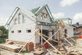 Unfinished modern farmhouse building. Wooden roof framing of mansard with dormer and aerated concrete block walls with windows. Royalty Free Stock Photo