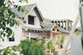 Unfinished modern farmhouse building. Wooden roof framing of mansard with dormer and vapor barrier on aerated concrete block walls