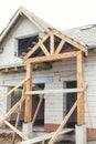 Unfinished modern farmhouse building. Wooden roof framing of mansard with dormer and vapor barrier on aerated concrete block walls