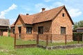 Unfinished red brick family house with worn down doors and faded window frames surrounded with rusted metal fence