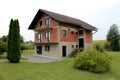 Unfinished red brick and grey building block family suburban house with new doors and windows surrounded with freshly cut grass