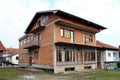 Unfinished red brick suburban family house with boarded front windows and doors surrounded with grass and other houses