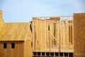 Unfinished roofing with OSB Oriented Strand Board plywood sheathing near timber frame house wooden posts beams under construction