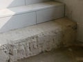 Unfinished tiling work on a concrete stairs - laying ceramic tiles on staircases