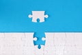 Unfinished white puzzle lying near last piece on blue background closeup Royalty Free Stock Photo