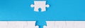 Unfinished white puzzle lying near last piece on blue background closeup Royalty Free Stock Photo