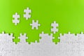 Unfinished white puzzle pieces on a green background Royalty Free Stock Photo