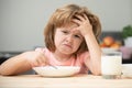 Unfocused little boy having soup for lunch. Unhappy Caucasian child sit at table at home kitchen have no appetite. Upset Royalty Free Stock Photo