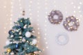 Unfocused shot. Blurry Christmas background with decorated fir-tree and  hanging pine cone wreaths with golden garland lights Royalty Free Stock Photo